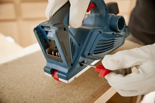 Man wearing gloves adjusting the depth on the Bosch cordless planer.