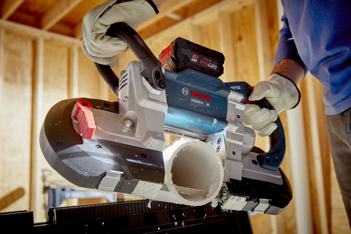 Bosch GCB18V-5 HD band saw cutting a white pipe, held by a person wearing work gloves.