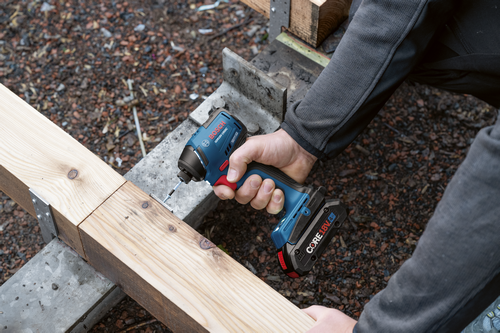 Bosch GDR18V-1950C impact driver screwing a screw into wood; the impact driver is powered by a CORE18V 4Ah battery.
