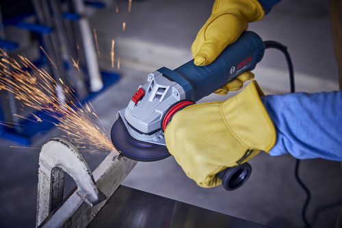 Bosch angle grinder with sparks. The grinder is blue and gray, held by hands wearing yellow work gloves.