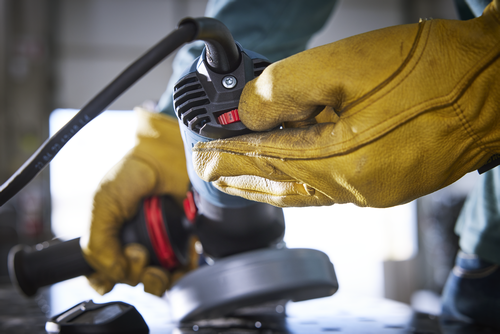 Person wearing yellow leather gloves using an angle grinder, with the red setting at "2".