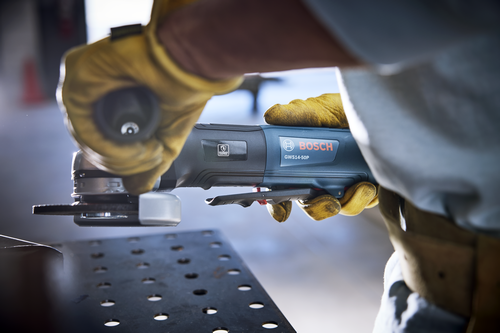 Bosch GWS14-50P angle grinder held by a person wearing yellow gloves.