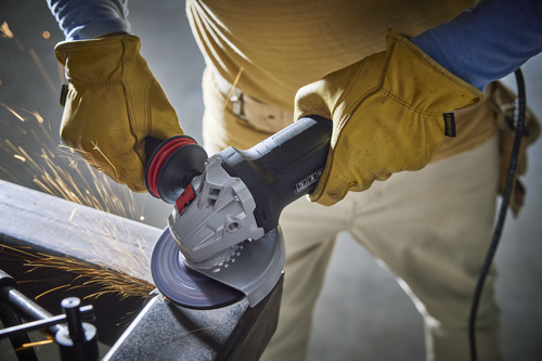 A person wearing gloves operates a grinder, with sparks visible.