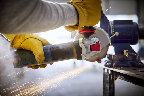 Person wearing yellow gloves using an angle grinder, with sparks flying.