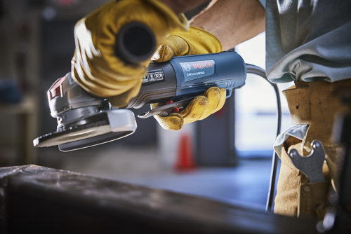 Bosch GWX14-50PBD angle grinder held by a person wearing yellow gloves.