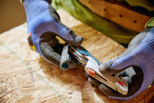 A person using the Bosch H11-13000-1 Retractable knife replacing the blade.