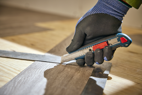 A person using the Bosch H11-12100-1 snap off knife cutting a wood material.