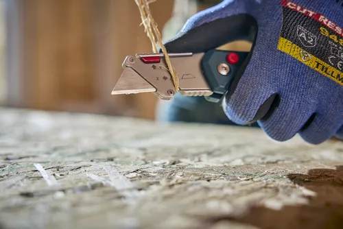 A person using the Bosch H11-11100-1 folding knife to cut a string.