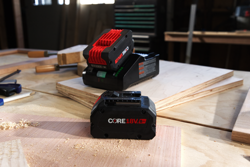 CORE18V batteries, red and black, on a plywood surface.