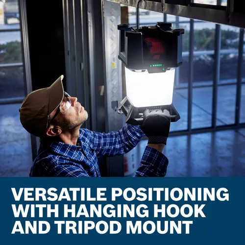 Man with a cap and safety glasses holding a light with visible text "VERSATILE POSITIONING WITH HANGING HOOK AND TRIPOD MOUNT".