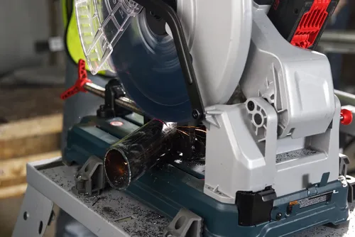 Bosch metal cutting saw cutting a metal pipe, producing sparks and shavings.