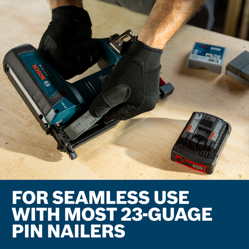 A worker holding a Bosch GNH18V-35 23-Gauge Pin Nailer and loading the nailer with 23 gauge pin nails on a work table.