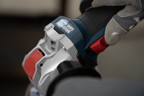 A close-up image of a worker adjusting the slide switch on the Bosch GWX18V-8-2 18V X-LOCK Brushless 4-1/2 In. Angle Grinder.