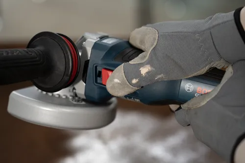 Close-up image of worker holding the Bosch GWS18V-11S 18V Brushless 4-1/2 – 5 In. Angle Grinder with Slide Switch.