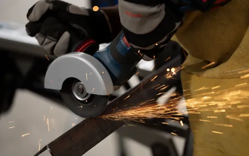 The Bosch GWS18V-11PS 18V Brushless 4-1/2 – 5 In. Angle Grinder with No Lock-On Paddle Switch in use for cutting a steel bar.