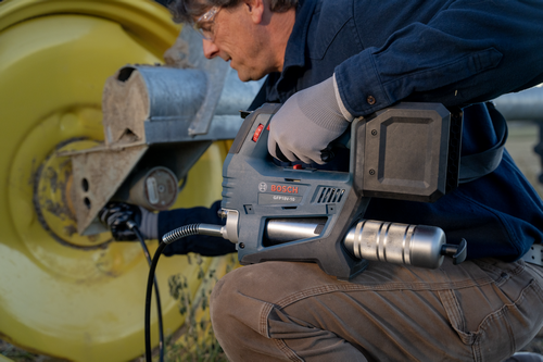 A worker using the Bosch GFP18V-10 18V Grease Gun on a vehicle wheel.