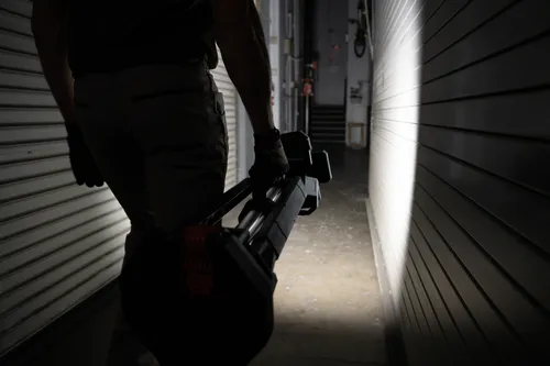 A worker holding the Bosch GLT18V-5000N 18V Tower Light to illuminate the dark path ahead.