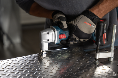 The worker using the Bosch GSC18V-16E 18V 16-Gauge Metal Shear with Lock- On Slide Switch to cutting a metal plate.