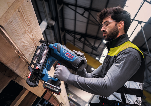 Image of worker using the Bosch EXNH18V-90MRN EXPERT 18V Framing Nailer on a wooden board.