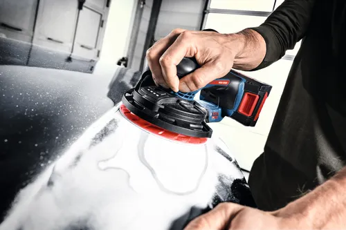 Image of worker using the Bosch EXEX18V-150-5N Random Orbit 18V 6” Random Orbit Sander (3/16”) for finishing a car.
