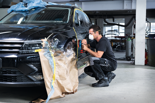 Image of worker using the Bosch GEX18V-150-3N 18V 6” Random Orbit Sander (3/32”) for finishing a car.