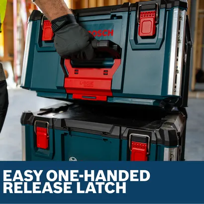 A gloved hand lifts a stacked Bosch L-Box contractor box by its red one-handed release latch.