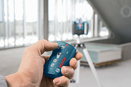 Bosch RC1 remote control, with arrow buttons, and other function buttons, in a person's hand.