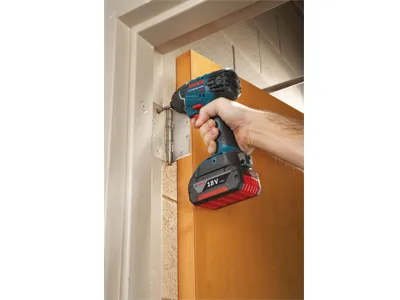 Visseuse à chocs Bosch 18V utilisée pour installer une charnière sur un cadre de porte.