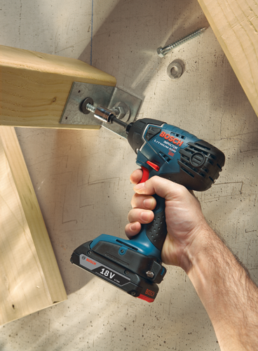 Une main utilisant une perceuse-visseuse à percussion Bosch Impactor Lithium-Ion 18V pour fixer une plaque métallique à une poutre en bois.