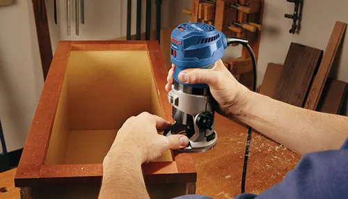 Routeur Bosch utilisé sur une boîte en bois.