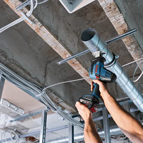 Bosch GSA 18V-083, 18V 4.0 Ah Li-ion, scie sabre sans fil, en utilisation près de conduits.