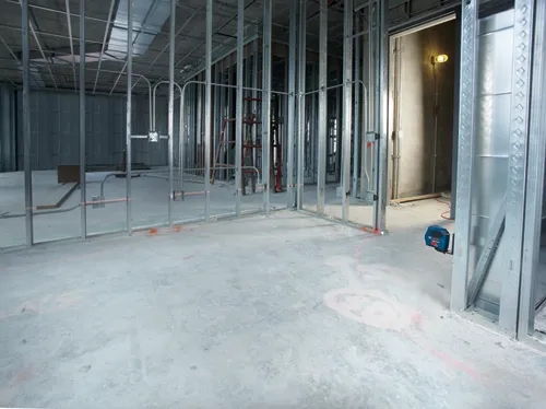 Voici la traduction :

Le niveau laser Bosch Professional est monté sur une ossature métallique d'un bâtiment en construction. L'intérieur inachevé présente des montants et des câbles électriques apparents.