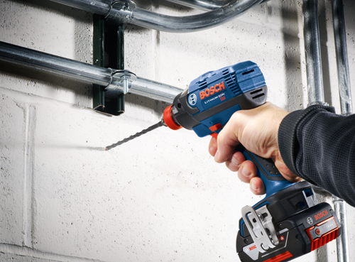 Perceuse sans fil Bosch LITHIUM-ION 18V utilisée pour percer un trou dans un mur blanc.