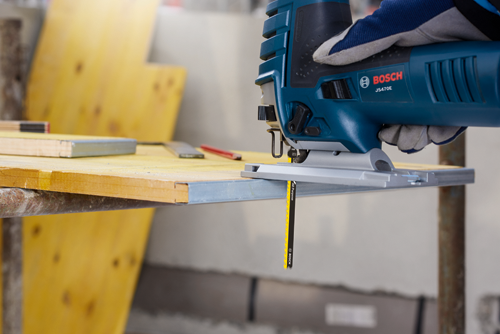 Scie sauteuse Bosch JS470E coupant une planche de bois, lame "All Purpose" visible.