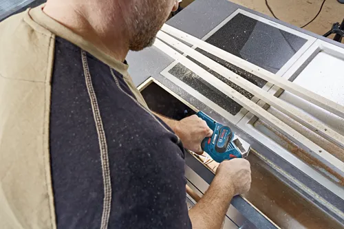 Homme utilisant une raboteuse sans fil Bosch GHO 12V-08 sur du bois.