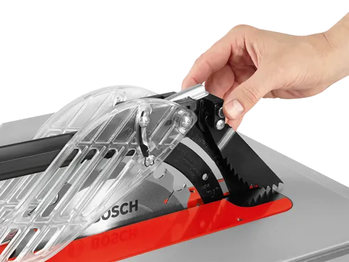 Scie à table Bosch avec une main ajustant le protecteur de lame.