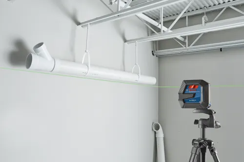 Bosch Professional GLL100-40G niveau laser vert émet une ligne laser verte, alignée avec un tuyau blanc suspendu au plafond.
