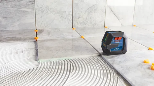Nível laser vert Bosch Professional GLL100-40G émettant un faisceau vert sur des carreaux.