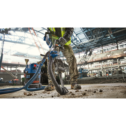 Voici la traduction :

Personne utilisant un aspirateur Bosch HAMMER, prêt pour HEPA, et portant un gilet de sécurité et des chaussures de sécurité sur un chantier de construction.