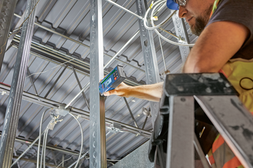 Personne utilisant un niveau sur une poutre métallique, chantier de construction.