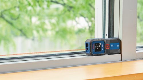 Bosch BLAZE télémètre laser affichant 4'11" 1/16 contre un encadrement de fenêtre.