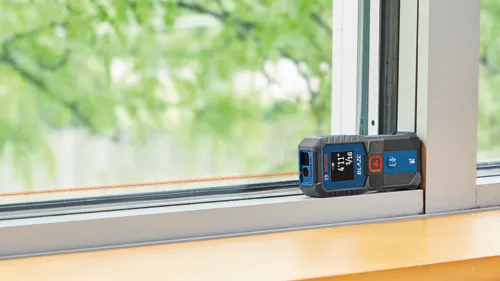 Bosch BLAZE télémètre laser affichant 4'11" 1/16 contre un encadrement de fenêtre.