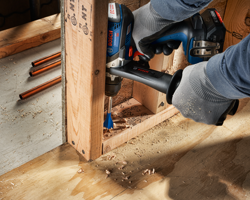 Perceuse sans fil Bosch 18V, perçant une ossature en bois ; « BOSCH » et « moteur EC » sont visibles.