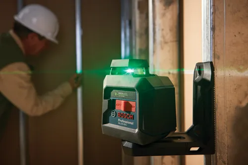 Niveau laser vert Bosch Professional GLL50-40G, avec faisceaux laser verts, monté sur un mur. Une personne portant un casque de protection est visible en arrière-plan.