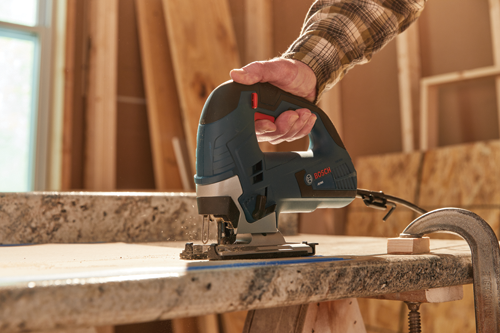 Scie sauteuse Bosch JS365 utilisée par une personne pour couper une surface en bois.