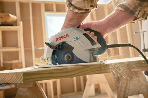 Homme sur un chantier de construction coupant du bois avec la scie circulaire filaire Bosch CS5.