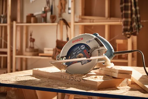 Scie circulaire filaire Bosch sur une pile de bois dans un atelier.