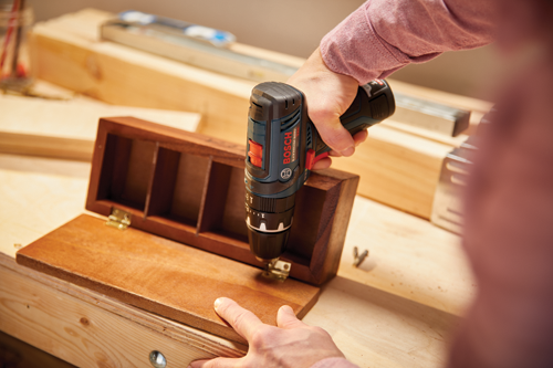 Perceuse Bosch Lithium-Ion utilisée pour percer une boîte en bois.