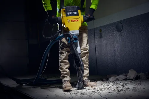 Ouvrier tenant un marteau piqueur Brute jaune et noir de Bosch, avec le texte "Vibration Control".