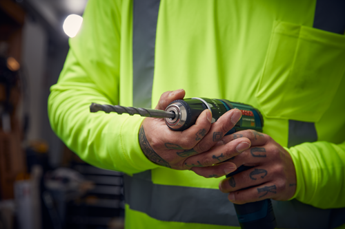 Homme tenant une perceuse Bosch Lithium-ion avec un foret à la main.